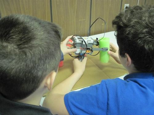 students measuring a tree trunk with a Lego caliper