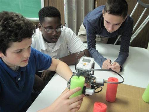 students measuring a tree trunk with a Lego caliper 