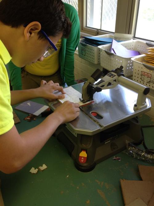 Stem Lab students using the scroll saw to execute the design of their jigsaw puzzle creation. 