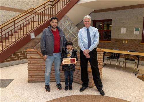 Diehl Stairclimber Mohamad Ebo posing with his plaque, family member, and Principal Tim Sabol.