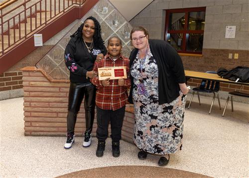 Lincoln Stairclimber Meelion Williams posing with his plaque, a family member, and Principal C.J. Huffman.
