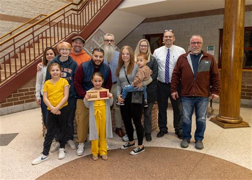 Jefferson Stairclimber Stella Fromyer posing with her plaque, family members, and Principal Jeff Boam.