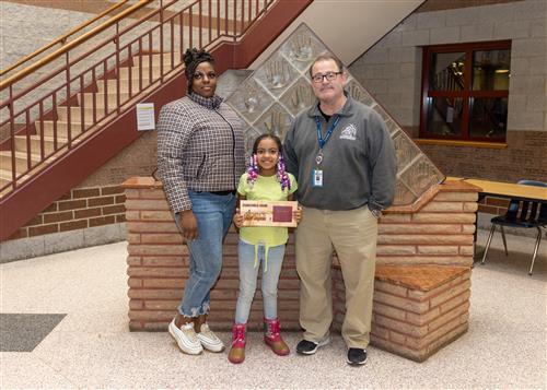 McKinley Stairclimber Justice Speed posing with her plaque, family member, and Principal Dana Suppa.