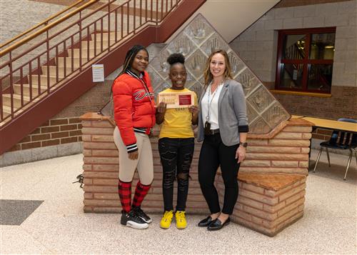 Wilson Stairclimber Rasheeda Cooley posing with her plaque, family member, and school assistant principal.
