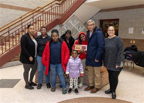 Pfeiffer-Burleigh Stairclimber Katora Spain posing with her plaque, family members and teacher.