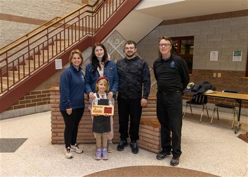 Perry Stairclimber Emma Zagurska posing with her plaque, family members, and Principal Dave Eubank.