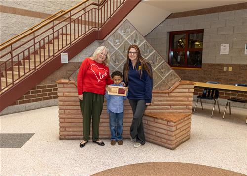 JoAnna Connell Stairclimber Noah Williams posing with his plaque, a family member, and a teacher.