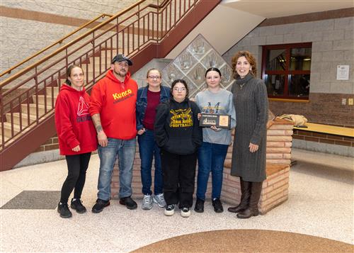Lhala Snyder, DiPaolo's November Stairclimber, poses with her picture, family members, and Principal Jill Crable.