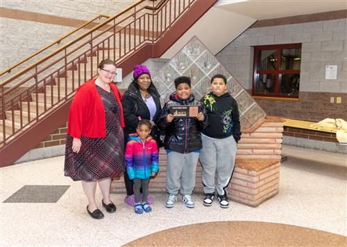 Pauly Harris, Lincoln's November Stairclimber, poses with his plaque, family members, and Principal Huffman.