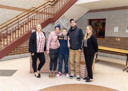 Jacob Sharpe, Pfeiffer-Burleigh's November Stairclimber, poses with his plaque, family members and school staff.