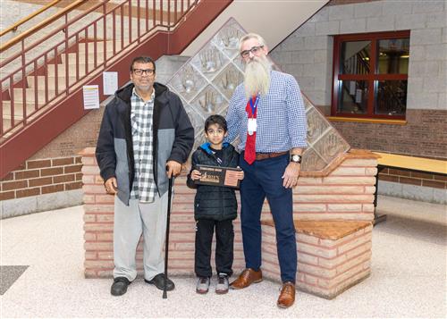 Hassan Al-Eisa, Jefferson's November Stairclimber, poses with his plaque, a family member, and Asst. Principal John Bayhurst.