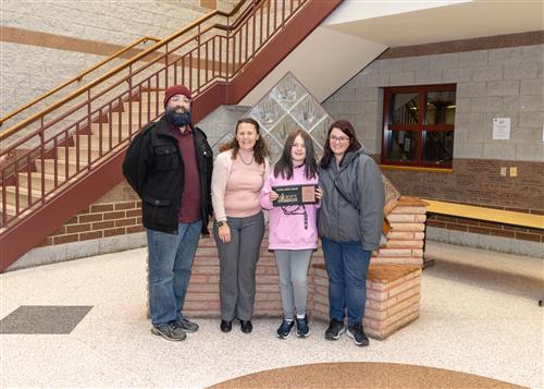 Liliana Van Cleve, Perry's November Stairclimber, poses with her plaque, family members and Principal Gunns.