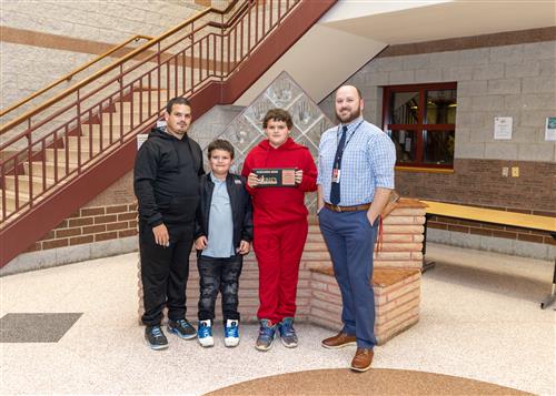 Nathan Herrington, East Middle's November Stairclimber, poses with his plaque, family members, and Principal Matt Koval.