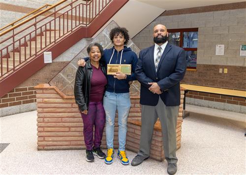 Erie High's March Stairclimber, Jamaree Nickson, posing with his plaque, a family member and DEI Coordinator Ken Nickson.