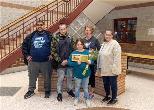 Grover Cleveland's March Stairclimber, Kristiniana Kelsey, posing with her plaque, family members and school staff.