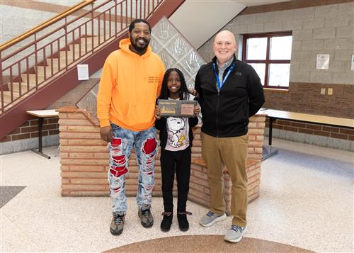 Jahira Delbrune, Perry Elementary's April Stairclimber, poses with his plaque, a family member, and EPS staff member.