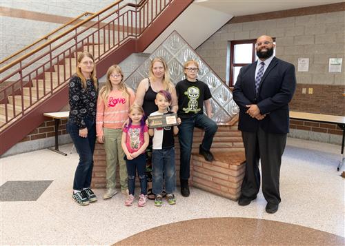 Dakota Schwab, Jefferson Elementary's April Stairclimber, poses with his award, family members and DEI Coordinator Nickson.