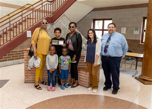 Kharaji Moye, JoAnna Connell Elementary's May 2023 Stairclimber, poses with his plaque, family, and Principal Causgrove.