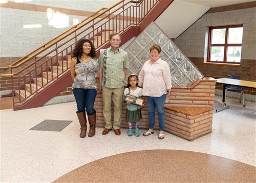 Azianna Miller, Harding Elementary's May 2023 Stairclimber, poses with her plaque, her teacher, and family members.