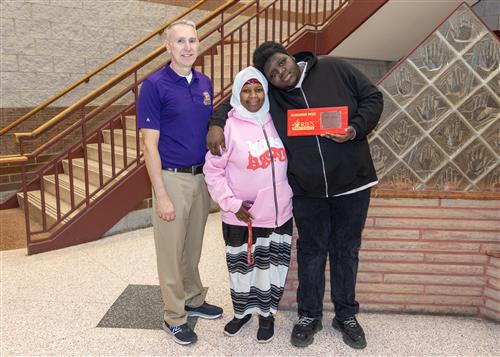 Armonii Torres, Erie High School's February Stairclimber, poses with his plaque, a family member, and AP Ryan Abbott.