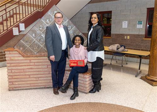 Ja'Braya Witherspoon, Collegiate Academy's February Stairclimber, poses with her plaque, a family member, and Dean Vieira.