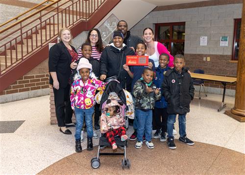 Ja'Zarion Walker, Pfeiffer-Burleigh's February Stairclimber, poses with his plaque, family members, and school staff.