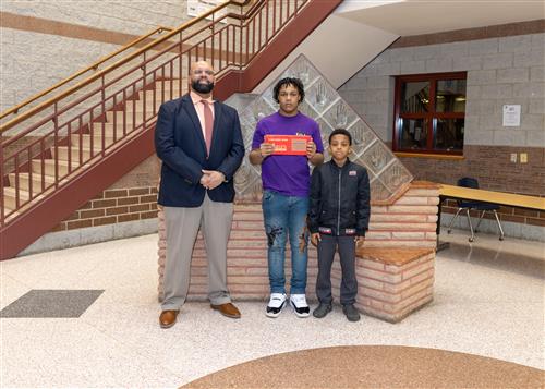 Jahmir Johnson, East's February Stairclimber, poses with his plaque, a family member, and Mr. Ken Nickson.