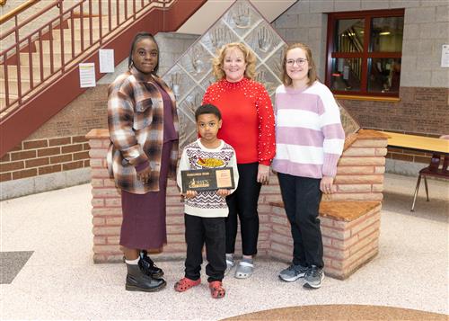 Elijah Clayton, Diehl's December Stairclimber, poses with his plaque, family members and school staff.