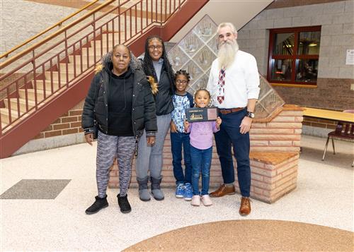 A'Zhailia Anderson, Jefferson's Stairclimber for December, poses with her plaque, family members, and AP Bayhurst.