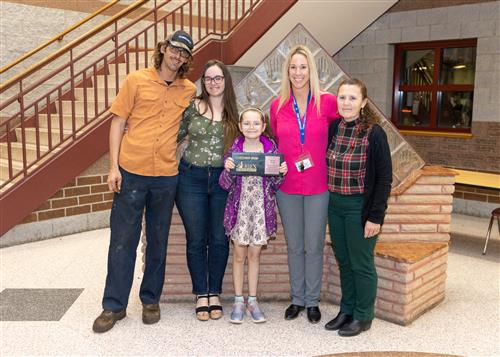Alexa Drayer, Perry's December Stairclimber, poses with her plaque, family members and school staff.