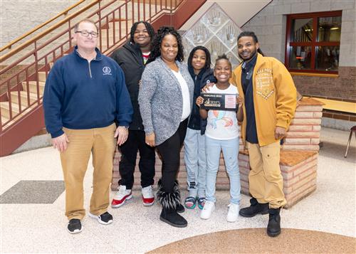 Za'Riyah Johnson, McKinley's December Stairclimber, poses with her plaque, family members and school staff.