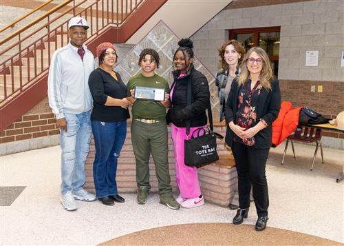 Jeremiah Sherrod, Emerson Gridley's December Stairclimber, poses with his plaque, family members and school staff.
