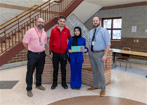 Amal Hasryeh, East's Stairclimber for March, poses with her plaque, family members, and school staff.