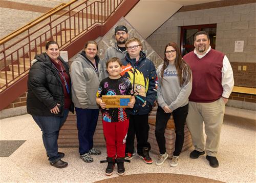 Tanner Savage, JoAnna Connell Elementary's December Stairclimber, posing with his plaque, family and Principal Rob Causgrove.