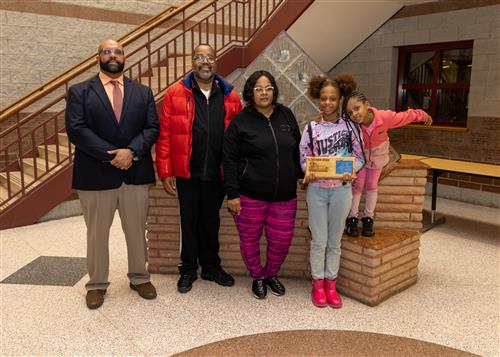 Serenity Guelledge, December Stairclimber from Eagle's Nest, poses with her plaque, family members and DEI Coord. Ken Nickson