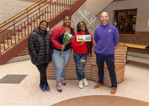 Dara'ja Brown, Erie High's December Stairclimber, posing with her plaque, family members, and Principal Don Orlando.