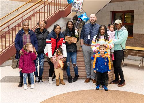 Dionni Carr, East Middle School's January 2023, poses with her plaque with family members and Principal Matt Koval.