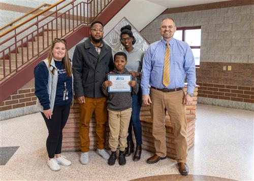 Photo of Aaron Davis standing with family members and Principal Jeff Boam.