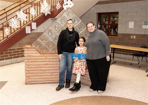 Bella Gatica, Lincoln's January Stairclimber, poses with her plaque, a family member, and Principal C.J. Huffman.