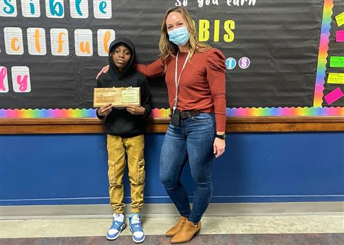 Wilson's March Stairclimber, Jamaris Moore, posing with his plaque and a member of the school staff.