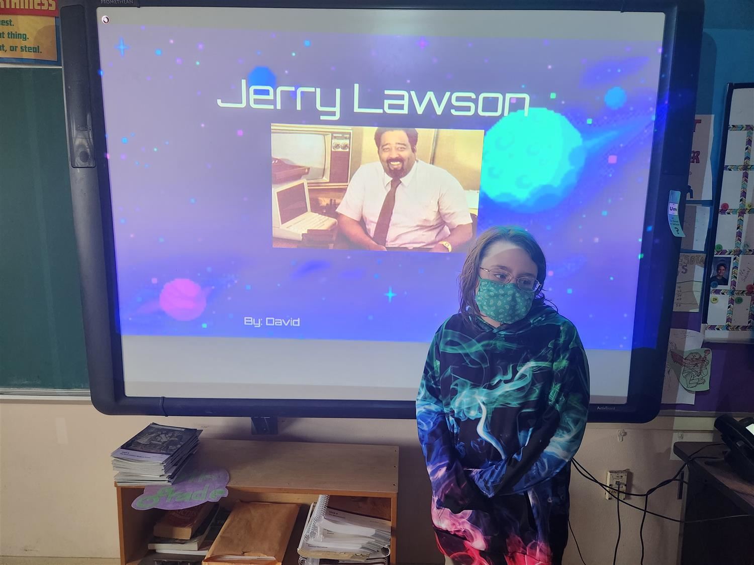 Student standing in front of a projector with a slide on it introducing Jerry Lawson.