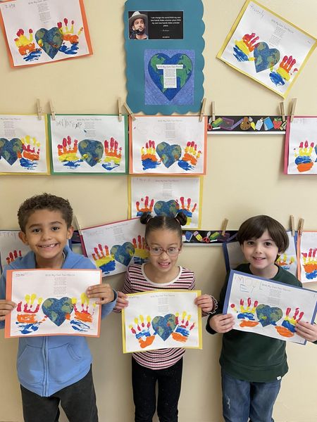 Three students displaying artwork of painted handprints with the typed lyrics of "With My Own Two Hands" by Ben Harper.