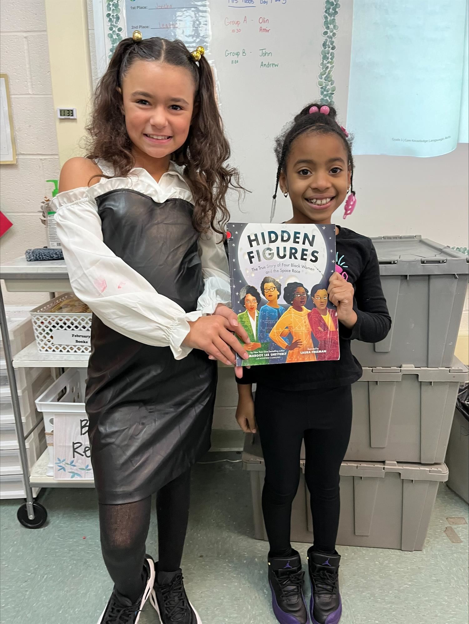 Two third-graders displaying the book "Hidden Figures."