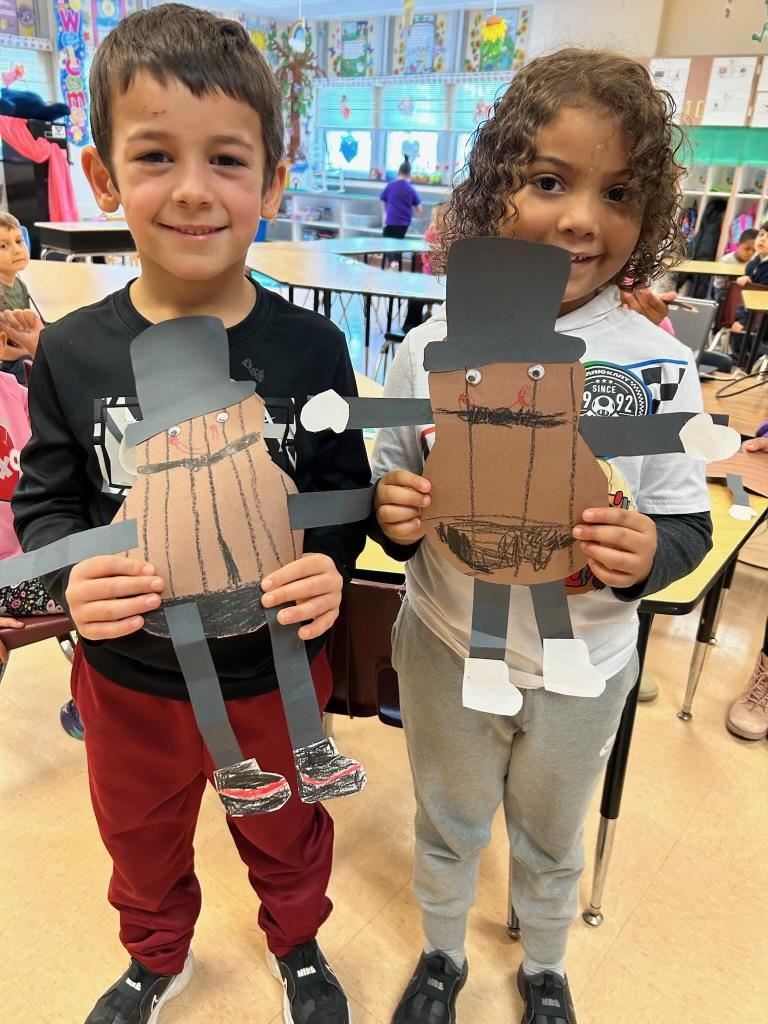 Two students holding peanuts made of construction paper.