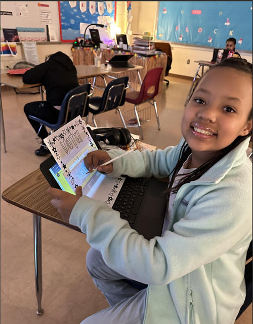 Female student sitting at desk smiles as she works on a worksheet creating a campaign slogan and poster.