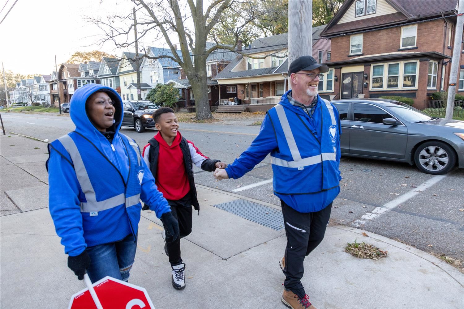 Picture shows two members of the Blue Coats peacekeeping initiative walking with a smiling male student.