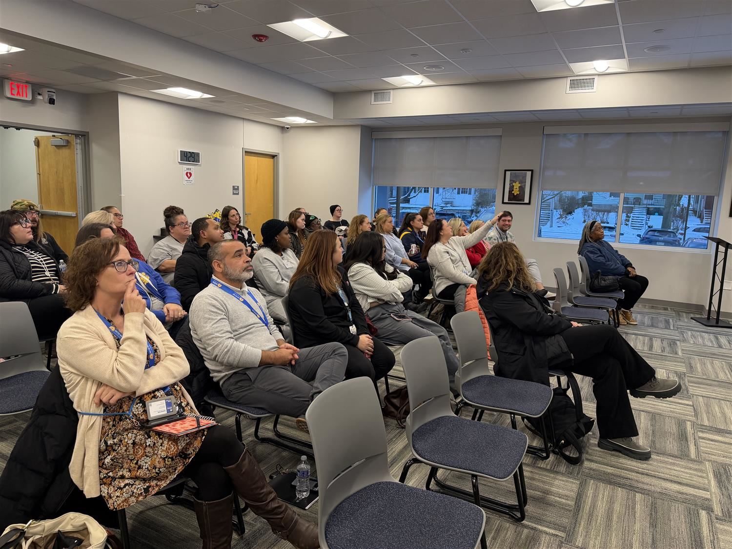Photo of a group of people sitting in rows of chairs participating in a focus group.