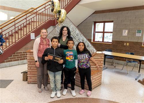 Angelo Kenner, Perry Elementary's May 2023 Stairclimber, poses with his plaque, family members, and school administrator.