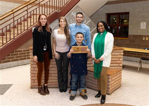 Kayleb Hallowell, January 2023 Stairclimber for Grover Cleveland, poses with his plaque, family members & Principal McFarland