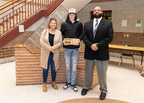 Ryan Gieza, January 2023 Stairclimber for Erie High School, poses with his plaque with family member & DEI Coord. Ken Nickson